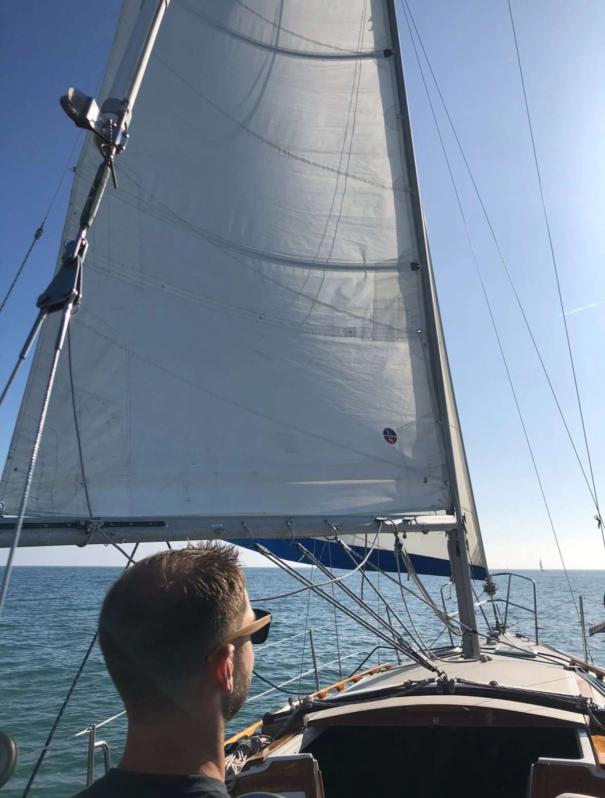Is it the wind, or is it how I've set the sail? Me in the cockpit of a sailboat under full sail on open water
