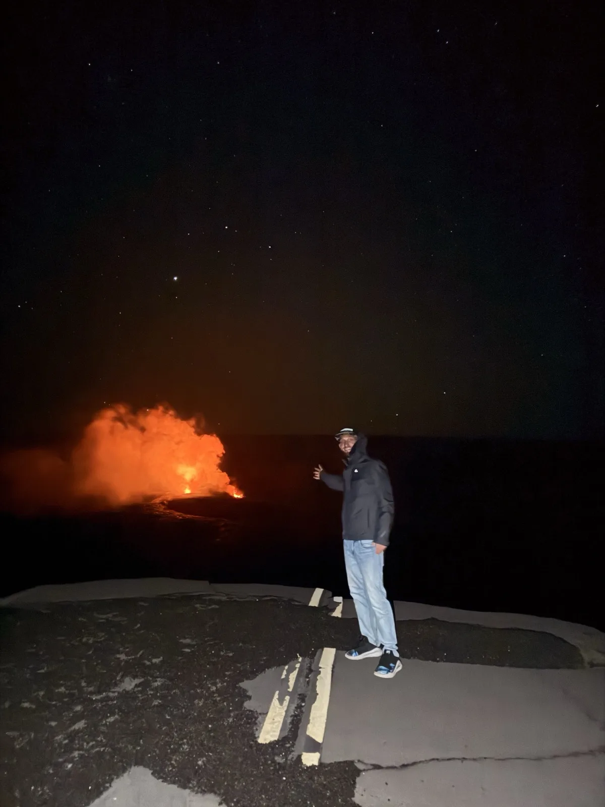 Standing at the edge of Kilauea volcano at night, lava glowing below and stars overhead | Zac Spowart sober travel Hawaii - Nomadic Addictt